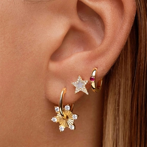 Close-up of gold ear hoops with star pendant and ruby stone on female ear