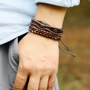 Detail of layered brown woven leather bracelets with adjustable pull string on a wrist