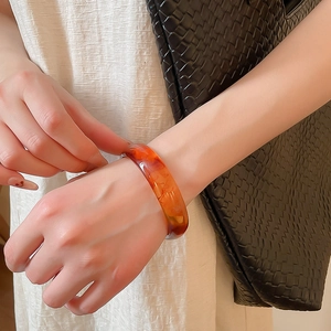 Close-up of translucent amber resin bangle with smooth finish worn by a model