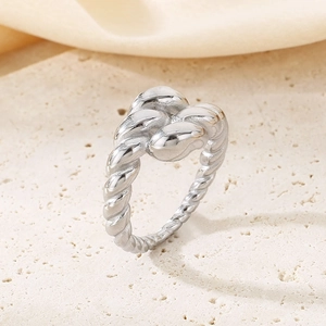 Minimalist silver twist knot ring made of stainless steel on beige stone background