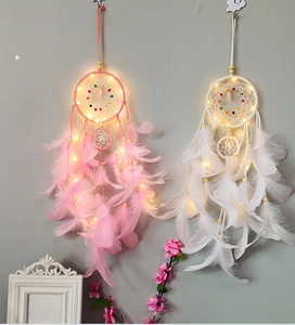 Detail eines rosa und weißen Traumfängers mit warmen LED-Lichtern und Federn