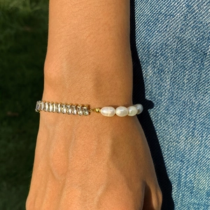 Close-up of a gold stainless steel bracelet with square zircons and fresh water pearls