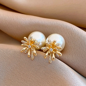 Close-up of luxury gold fireworks earrings with large white pearls and clear zircon stones