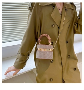 Pink rhinestone cylinder bag with metal chain strap worn on olive green trench coat