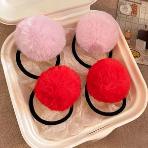 Detailed view of pink and red faux fur pom pom hair ties in a gift box packaging