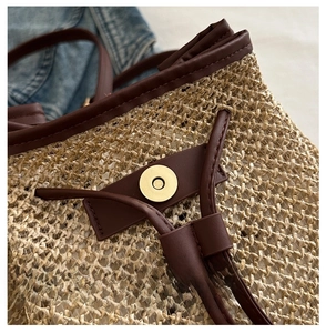 Detail of golden metal magnetic buckle and straw weave texture on a summer bag