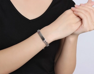 Dettaglio del bracciale a catena in acciaio argento con piastrina e simbolo medico