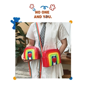 Detail of glossy rainbow striped crossbody bag with red heart and wide strap