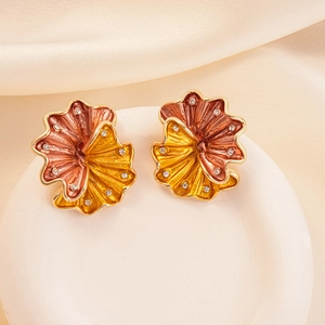 Detailed shot of pleated fan-shaped flower earrings with crystals on a ceramic tray