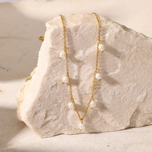 18K gold stainless steel chain necklace with white pearls on a natural stone background