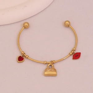 Detail of gold-plated bangle with red heart, miniature handbag, and red lip charms