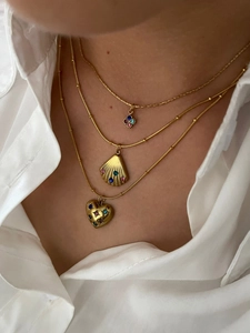 Close-up of layered gold necklaces featuring shell, heart, and flower pendants with zircons