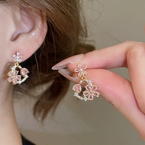 Close-up of model wearing 18k gold flower earrings with pink heart stones and diamonds
