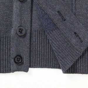 Macro detail of dark grey knit cardigan with black buttons and ribbed hem finish