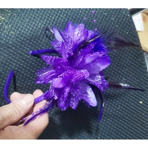 Detail of purple feather fascinator with mesh veiling, fabric flowers and beads decoration