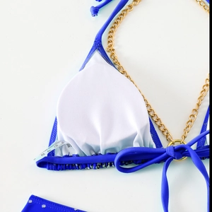 Detailed macro view of royal blue bikini top with gold chain straps and white removable pads