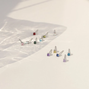 Close-up of small titanium steel stud earrings with colorful birthstone cubic zirconia