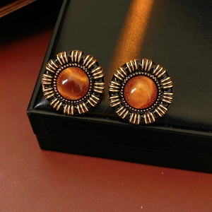 Macro shot of vintage amber resin earrings with antique gold frame and sunburst pattern