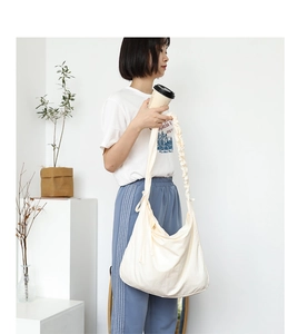 Detail view of cream white canvas shoulder bag with unique pleated strap design