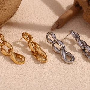 Macro detail of intertwined three-link chain earrings in polished gold and silver finishes