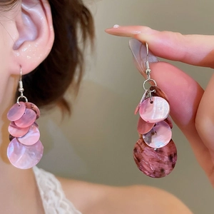 Détail des boucles d'oreilles pendantes en nacre rose portées par un mannequin en gros plan
