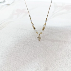 Detail of gold cross pendant with clear zircons and white pearls on a fine necklace