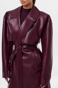 Détail d'un trench-coat en cuir bordeaux avec col à revers et ceinture sur mannequin