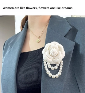 Detail of camellia brooch with pearl fringe tassels on a dark grey blazer lapel