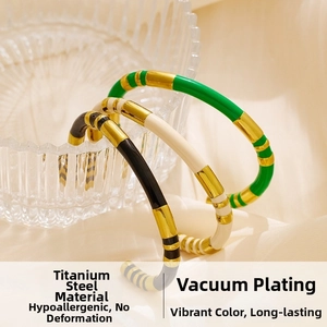 Detail of gold-plated titanium steel cuffs featuring green, cream, and black enamel accents