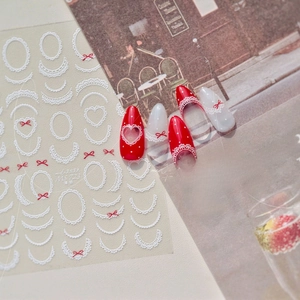 Macro detail of MS 723 nail art stickers with white lace and red bow designs on nails