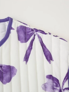 Detail view of white quilted fabric with purple floral print and piping on the jacket