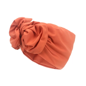 Detail eines korallenorangen Turban-Stirnbands mit Knoten und elastischer Stoffstruktur