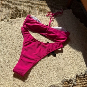 Flat lay of hot pink two-piece bikini with starfish embroidery and side-tie bikini bottom