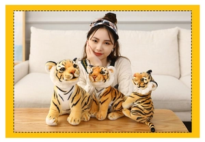 Three realistic tiger plush toys in various sizes shown by a model on a sofa