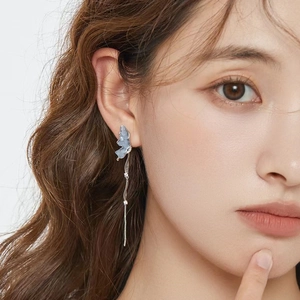 Close-up of model wearing blue butterfly tassel earrings with sparkling rhinestones