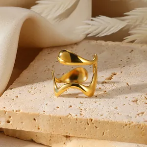 Detail shot of a polished golden wave ring on a stone base with soft satin and dried flowers