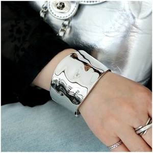 Close-up of a wide polished silver cuff bracelet worn with modern fashion attire