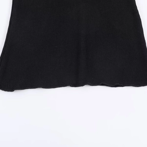 Macro detail of black ribbed knit fabric showing texture and wavy hem stitching