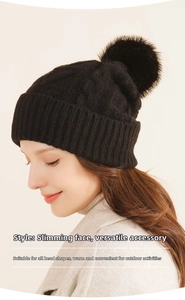 Close-up of a black chunky knit beanie featuring a fluffy pom-pom on top for winter wear