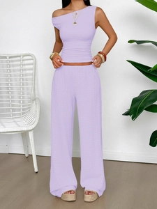 Detail of lavender two-piece set featuring a textured one-shoulder top and wide-leg trousers