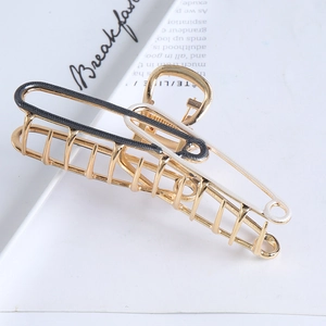 Macro view of gold metal hair claw clip with black and white enamel drip oil finish