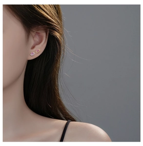 Close-up of Saturn planet stud earrings with pink purple crystal on model ear