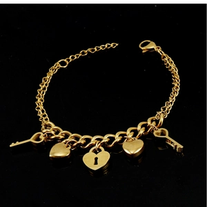 Détail du bracelet en acier inoxydable 18K avec breloques serrure cœur et clé dorées