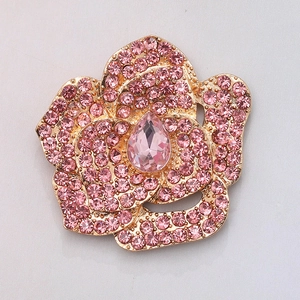 Macro view of flower charm with pink crystals and a central teardrop stone in gold finish
