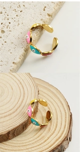 Detail of 18k gold-plated evil eye ring with colorful enamel inlay on stone background