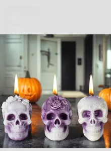 Detailed skull shaped candles with intricate rose carvings used in Halloween decor