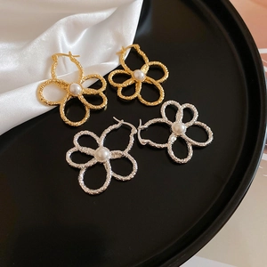 Close-up of gold and silver metal flower earrings with pearls on black tray