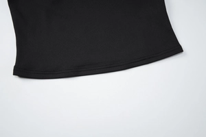 Close-up of the ribbed knit fabric and double-needle stitching on black vest hemline