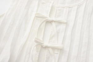 Detailed view of white pleated linen cotton fabric with decorative bow tie closure