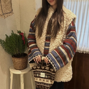 Close-up of cozy plush lamb wool vest paired with a colorful striped knit tote bag
